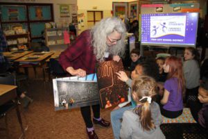 Museum Educator Naomi Meyer shows School 14 students artwork by Victor Ekpuk