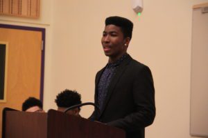 Male student stands at podium to debate raising the minimum wage. 