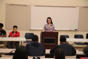 Female student stands in front of her peers to debate raising the minimum wage. 