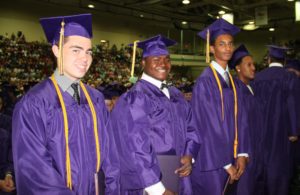 Three Troy high school graduates in cap and gown.