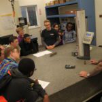 Students standing around a table learning about Simmons Machine Tool