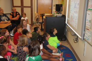 Students and parents watch the slideshow they made for their recycling project