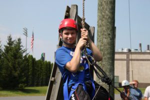 Male student in helmet and harness as he prepares for the ropes course