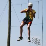 Male student in helmet and harness suspended in the air