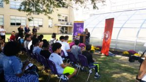 Dr. Donna Watson addresses the crowd in front of greenhouse