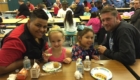 two dads and their young daughters eating breakfast