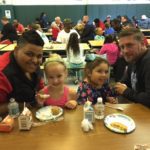 two dads and their young daughters eating breakfast