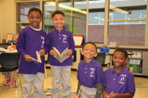 Four boys in purple School 2 shirts smile for the camera