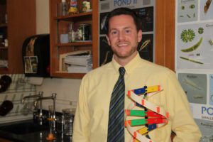 Justin Haviland in science classroom holding a model of a DNA strand