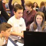 School 18 male students show conference attendees a project on a laptop