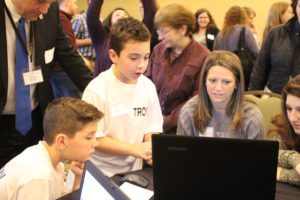 School 18 male students show conference attendees a project on a laptop