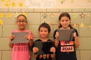 Three school 16 elementary students hold iPads