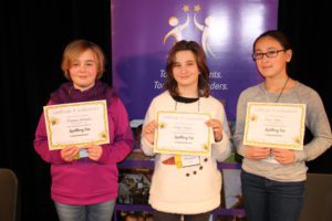 The three girls who won the spelling bee holding their certificates