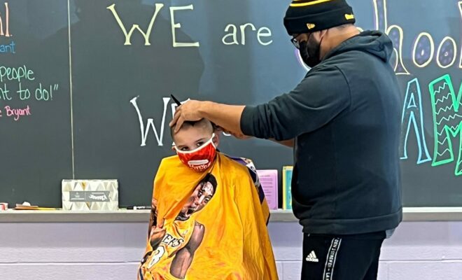 Photo of barber cutting young boys hair with a yellow cape