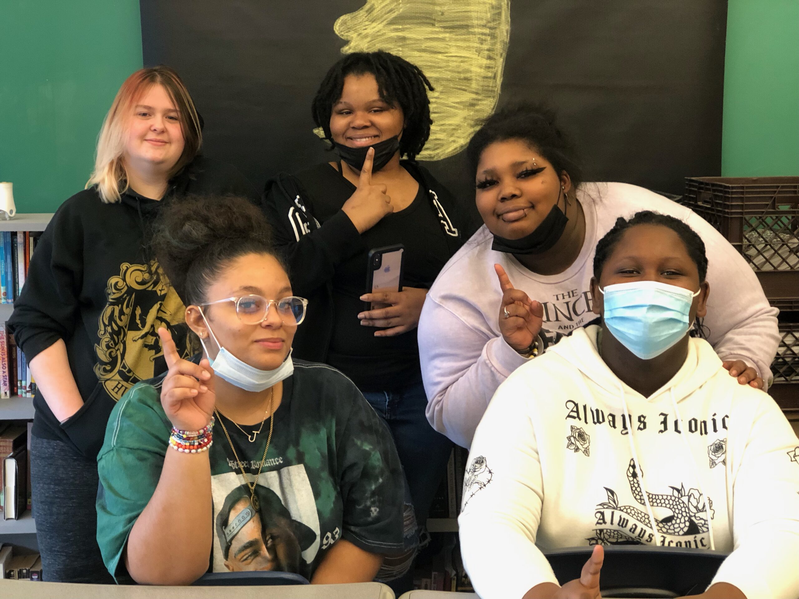 A group of five female students holding up one finger.