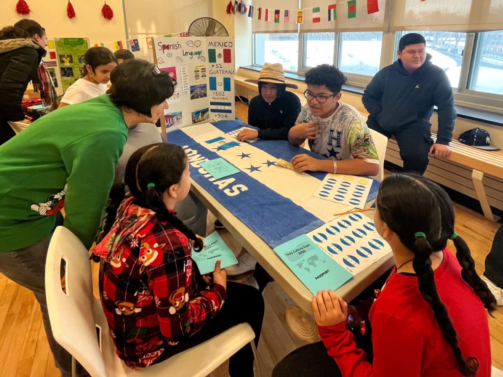 photo of several children sitting around a table with a display of information about Honduras