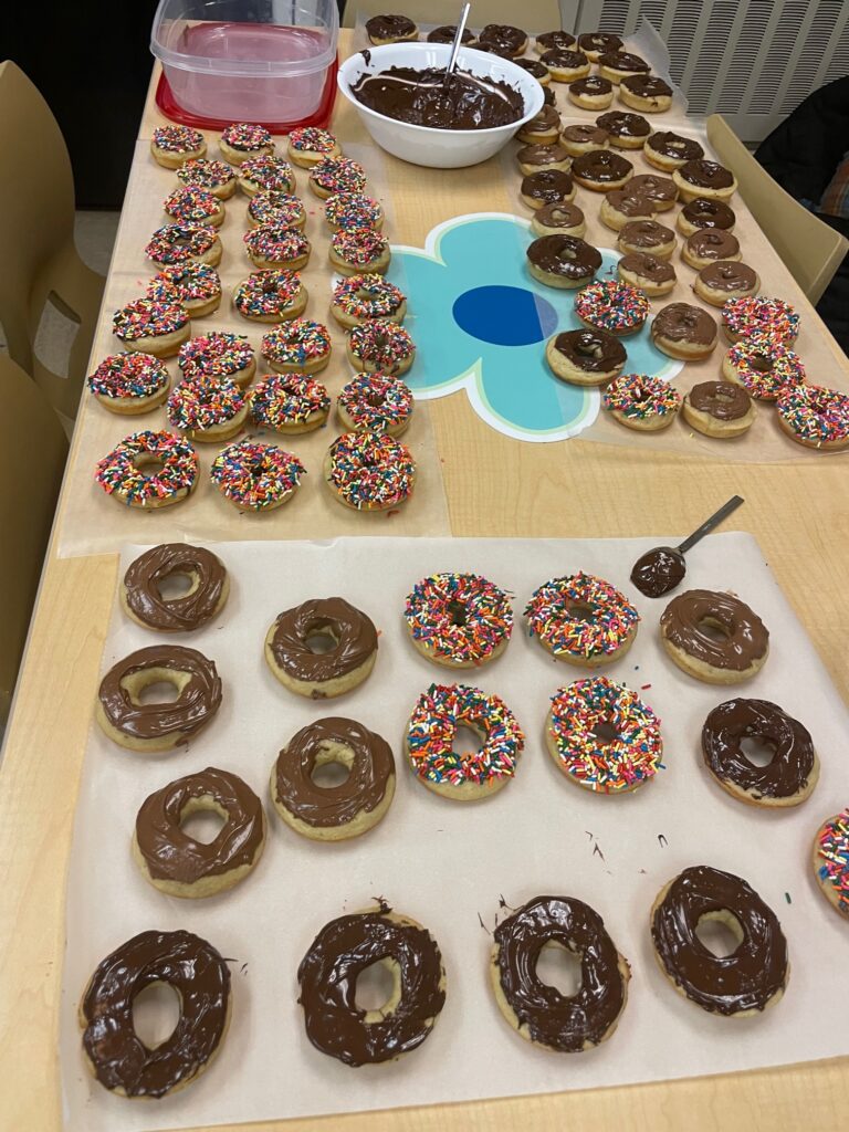 homemade chocolate frosted donuts are laid out on a table with a bowl of chocolate frosting.