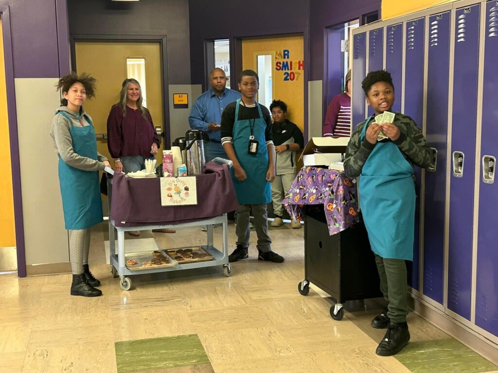 students and teachers pose in a hallway with the rolling cafe carts