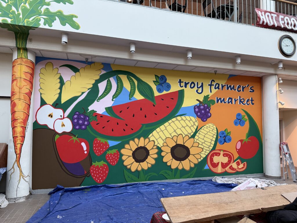 Completed vibrant mural at Troy Farmer's Market featuring colorful fruits, vegetables, and 'troy farmer's market' text