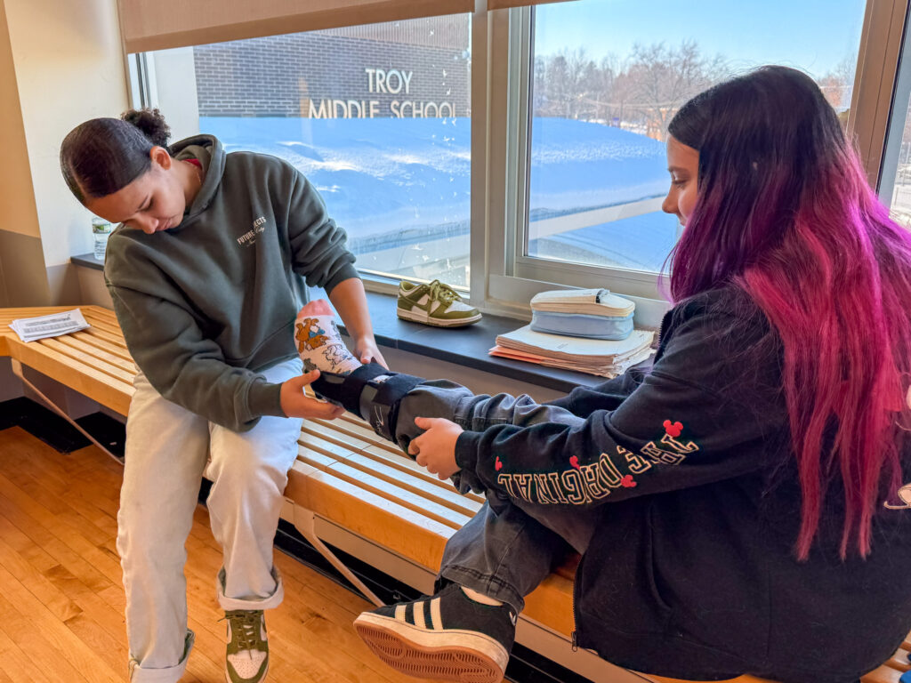 A student practices placing a splint on another student's ankle.